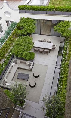 an aerial view of a courtyard with tables and benches surrounded by greenery on the roof