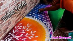 a man painting on the ground next to a brick wall with words written in english