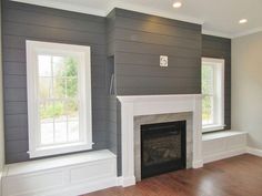 an empty living room with gray walls and white trim on the fireplace mantels