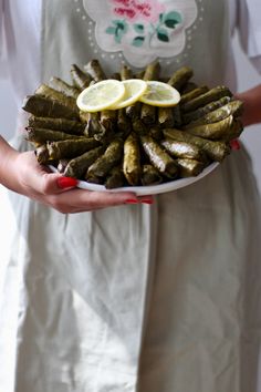 a woman holding a plate with lemons and other food items on it in her hands