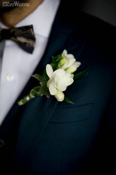 a man in a tuxedo wearing a boutonniere with white flowers