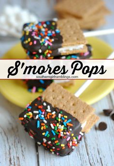 some cookies and marshmallows are on a yellow plate with the words s'mores pops