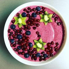 a bowl filled with berries and kiwis on top of a white countertop