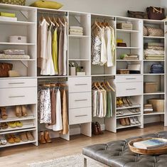 an organized walk in closet with white shelves and drawers