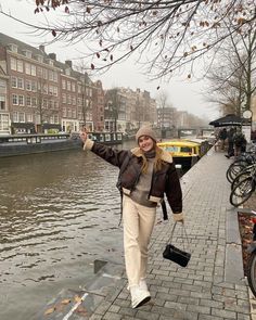 a woman is walking along the water with her hand in the air and she is smiling