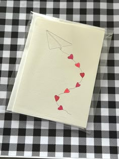 a piece of paper with hearts attached to it sitting on a checkered table cloth