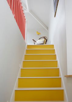 the stairs are painted bright yellow and red with white railings on each side, leading up to an upstairs bedroom