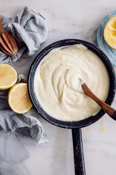 a pan filled with white sauce next to sliced lemons and cinnamon on a table