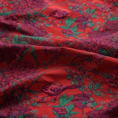 red and green floral print fabric with large flowers on the bottom right half of the image