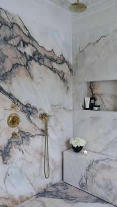 a white and black marble bathroom with gold faucet, shower head and hand shower