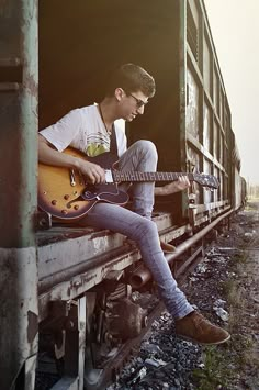 a man sitting in the back of a train holding a guitar