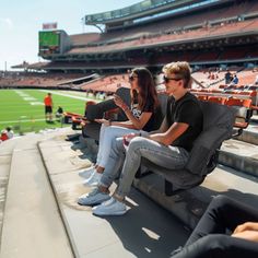 two people sitting on a bench at a football game