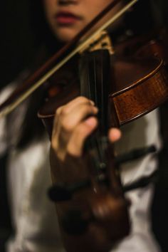 a woman is playing the violin with her hands