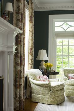 a living room with two chairs and a table in front of a window filled with curtains