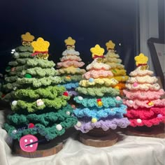 small crocheted christmas trees on display in front of a window with white curtains