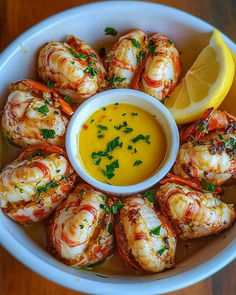 a white bowl filled with shrimp next to a lemon wedge and dipping sauce on the side