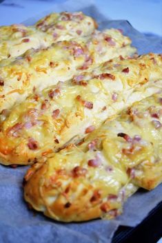 several cheesy breads with ham and cheese on them sitting on a piece of wax paper