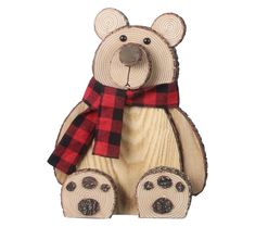 a wooden bear with a red and black plaid scarf on it's neck sitting in front of a white background