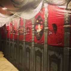 a hallway with red and black walls covered in white netting, decorated with pictures on the wall