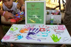 a little boy sitting in front of a table with hand prints on it and an easel