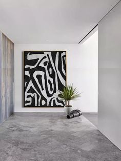 an abstract painting hangs on the wall next to a potted plant in front of it