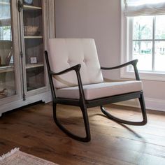 a rocking chair sitting in front of a window