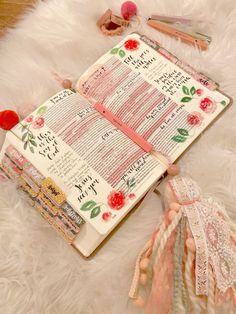 an open bible laying on top of a white fur covered floor next to other items