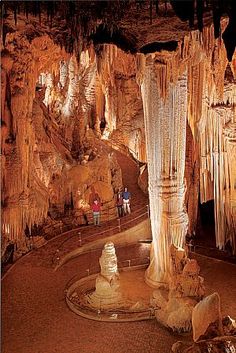 the inside of a cave filled with lots of stalate formations and people walking around