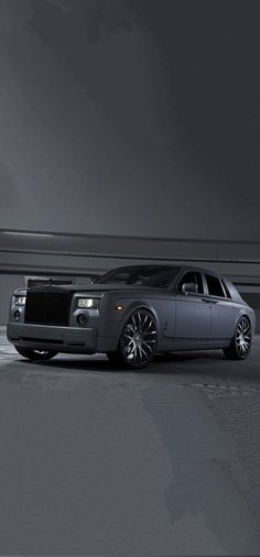 a silver rolls royce parked in front of a building with dark clouds above it and an empty parking lot