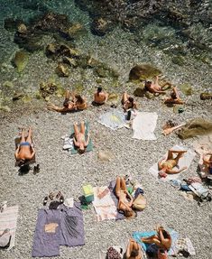 people are laying on the beach with towels