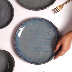 a person holding a blue plate on top of a white table with plates and silverware