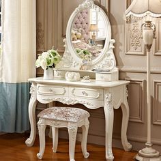 a white dressing table with a mirror and stool