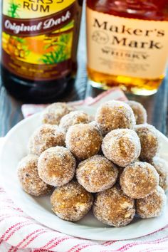 a white plate topped with sugar covered doughnuts next to a bottle of rum