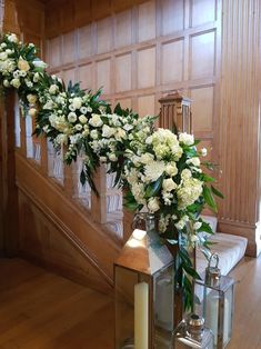 white flowers and greenery are arranged on the stairs