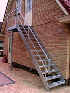 a metal stair case next to a brick building