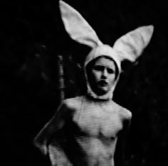 a man wearing a bunny costume in the dark with his head turned to look like an alien