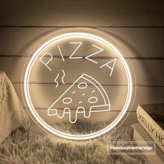 a pizza neon sign on the wall next to a book and pillow in a room