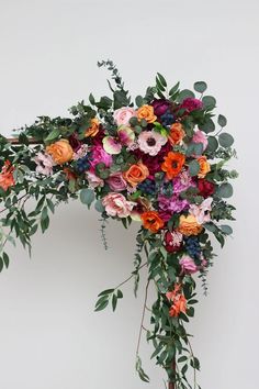 an arrangement of flowers and greenery on a white background