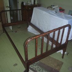 a bed frame with a white sheet on top of it