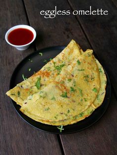 an eggless omelette on a black plate next to a cup of tea