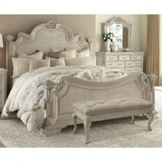 a white bed sitting in a bedroom next to a dresser and footboard with a mirror on top of it