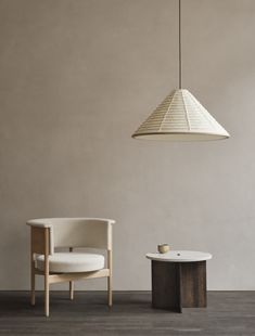 a white chair sitting next to a table on top of a hard wood floor under a light fixture