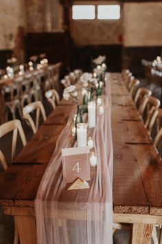 the table is set with candles and place cards for guests to sit down at it