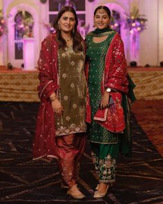 two women standing next to each other in front of a stage with lights and decorations