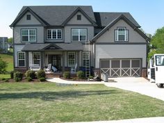 a large gray house with lots of windows on it's sides and two cars parked in front