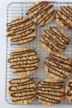 several cookies with chocolate drizzled on them sitting on a cooling wire rack