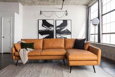 a living room with a couch, rug and two paintings on the wall behind it