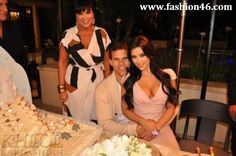 two women and a man sitting at a table in front of a cake with candles on it