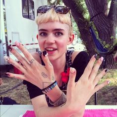 a woman sitting at a table with her hands in front of her face and fingers out