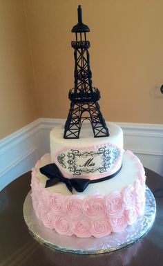 a three tiered cake with the eiffel tower on it's side